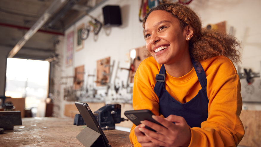 A business owner happily stands at a counter in her shop