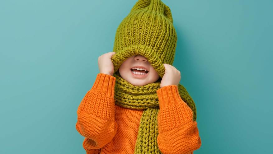 A child pulls a warm winter hat down over his eyes