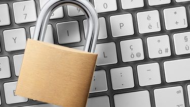 Locked pad lock sitting on top of grey keyboard.