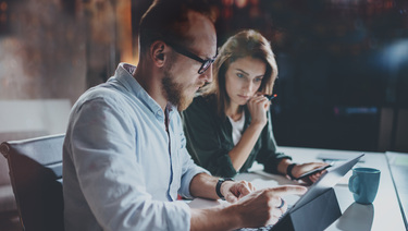 A concerned man and woman reading a computer tablet