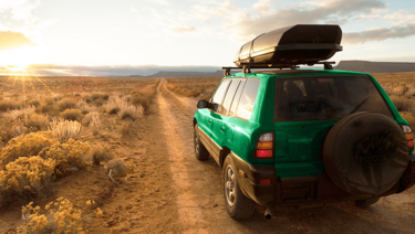 A small SUV is parked on a desert off-road