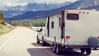 A truck pulls an RV on a mountain road