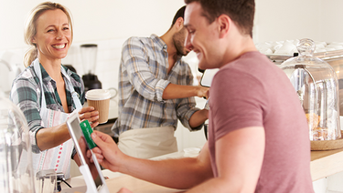 A man pays at a cafe with the digital wallet on his mobile device