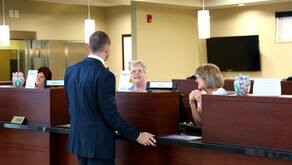 a customer talks to bankers in the teller line