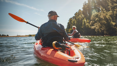 A mature couple kayaks on a mountain lake
