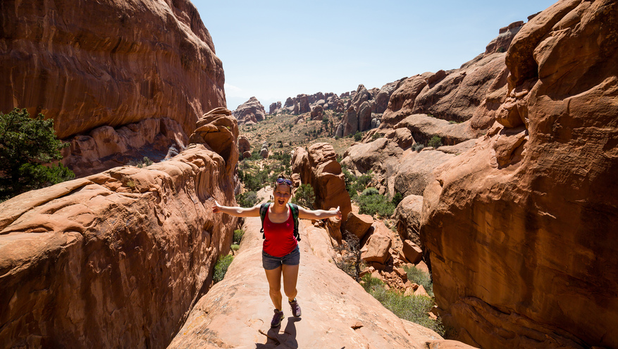 A woman happily goes up a red-rock trail in Utah