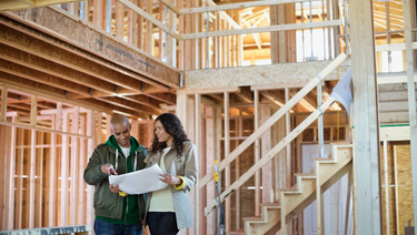 A young couple reviews plans in their home that is under construction