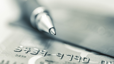 Close up of pen sitting on two credit cards.