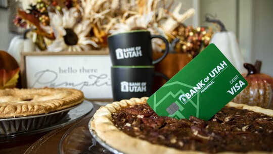 A Bank of Utah debit card placed on top of a pecan pie, in a fall table-scape