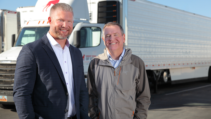 Bill Nehmer, owner of Great Dane of Utah, stands outside his Salt Lake City dealership with Bank of Utah's Brady Fosmark