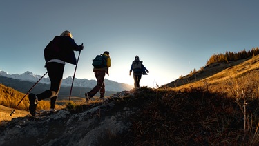 three hikers climb a mountain