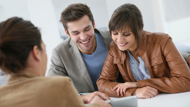 Services and Benefits - Young couple reading papers and smiling.