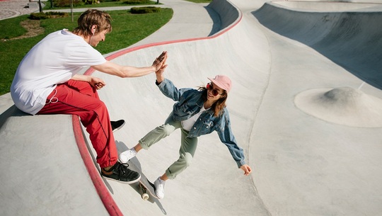 Two skateboarders have fun at a skate park