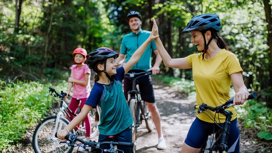 A family of four - a mom, dad and two daughters - enjoy a bike ride on a mountain trail