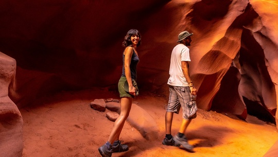 A male and female hike a slot canyon in Southern Utah