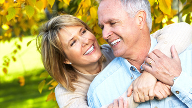 Older couple embracing and smiling at each other. 