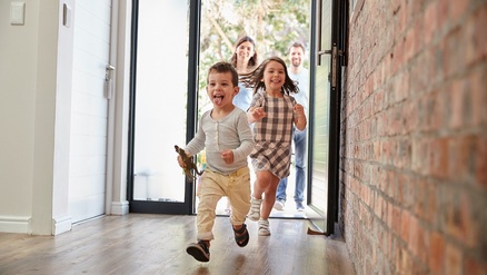 young family running into new home