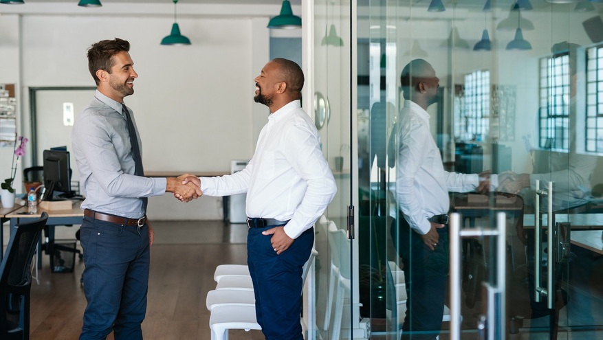 Two professionals shaking hands in a modern office, representing a successful banking partnership or financial service agreement	