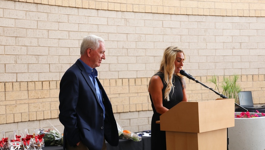 Frank Browning, Bank of Utah board chairman, stands beside a podium as a woman speaks into the microphone during the Ogden Rotary Club’s Brent Richards Legacy Award presentation.