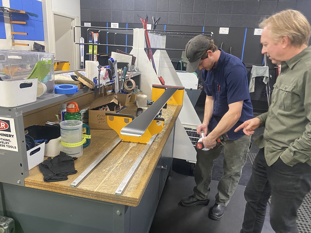 A team member at Alpine Sports waxes skis at a workbench.