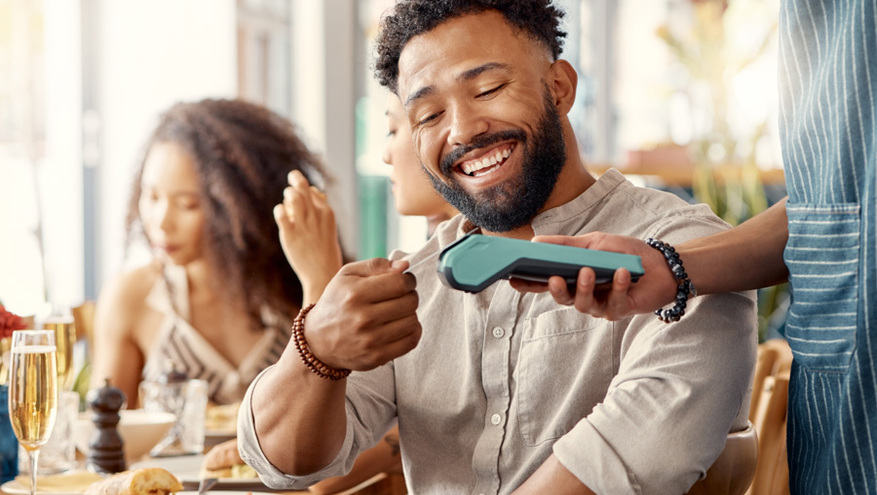 young couple smiling using tap to pay at a restaurant 