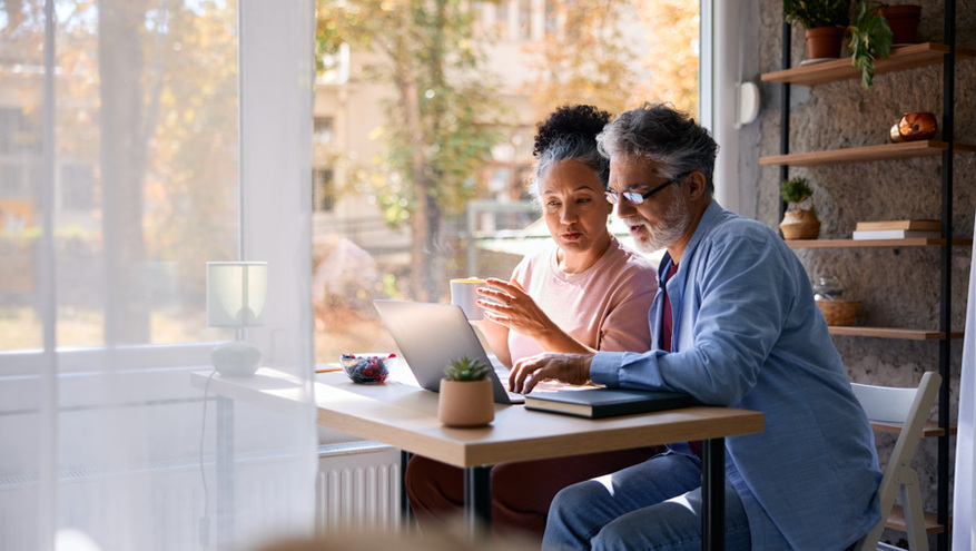 an older couple sit together using a laptop