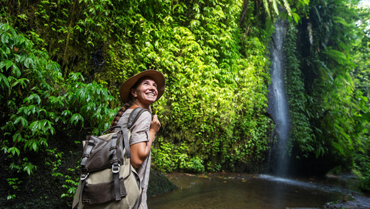 young woman exploring a jungle waterfall