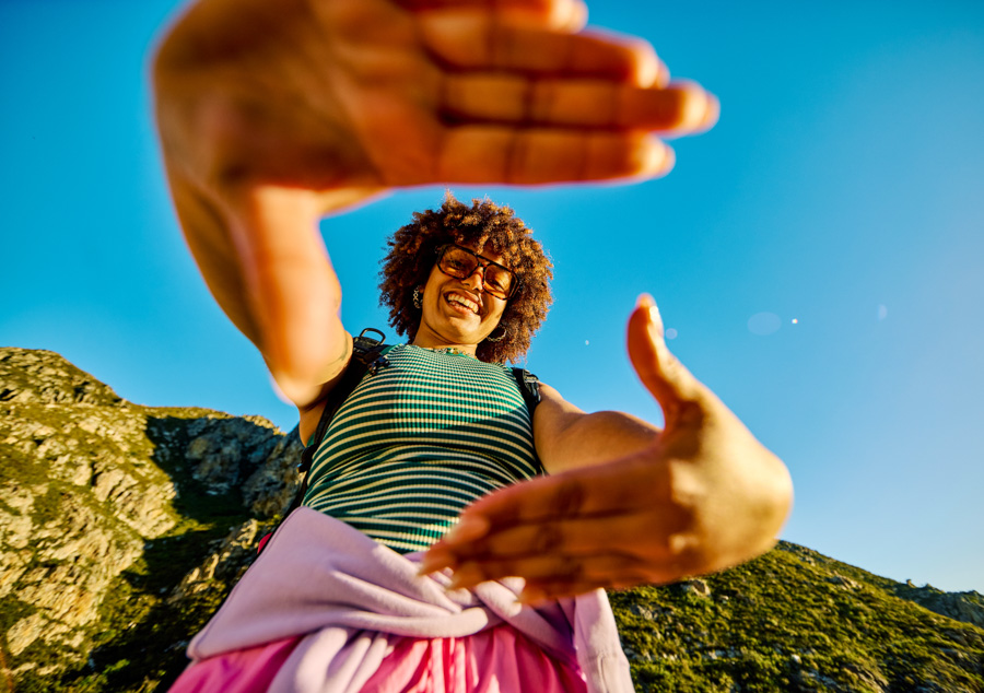 young woman in mountains using hands to make a frame
