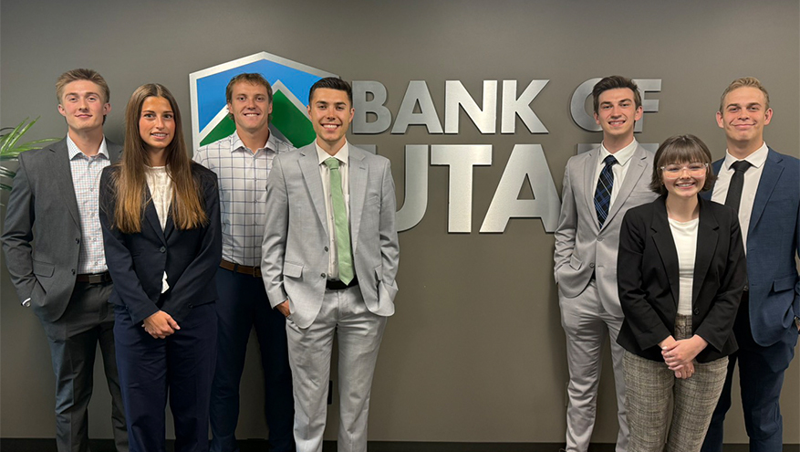Photo of a group of Bank of Utah interns with the BOU logo in the background