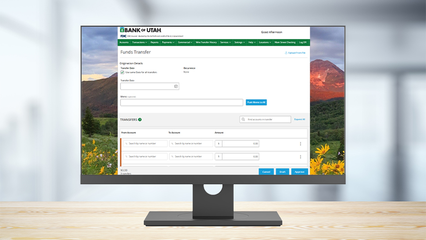 Computer monitor sitting on a wooden desk displaying Bank of Utah's online banking interface on a Funds Transfer screen.