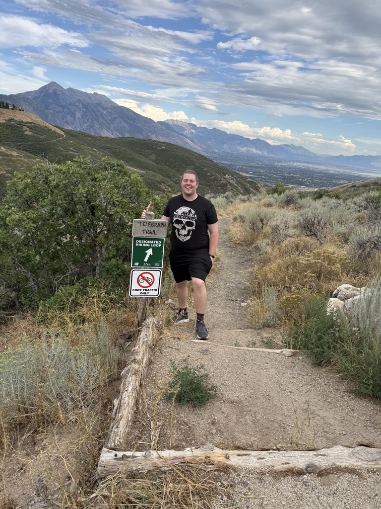 Bank of Utah Where’s the Wallet winner Aiden Jonkman on Telegraph Trail next to a wooden trail sign.