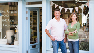 Young couple standing out front of their new local business.