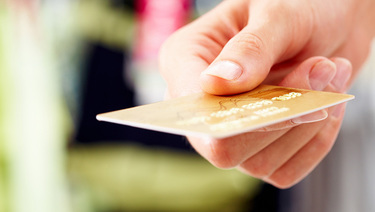 Close up of hand holding out credit card.