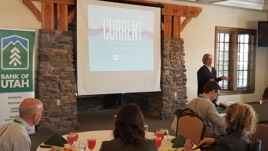 Photo of Natalie Gochnour speaking to an audience with a presentation slide