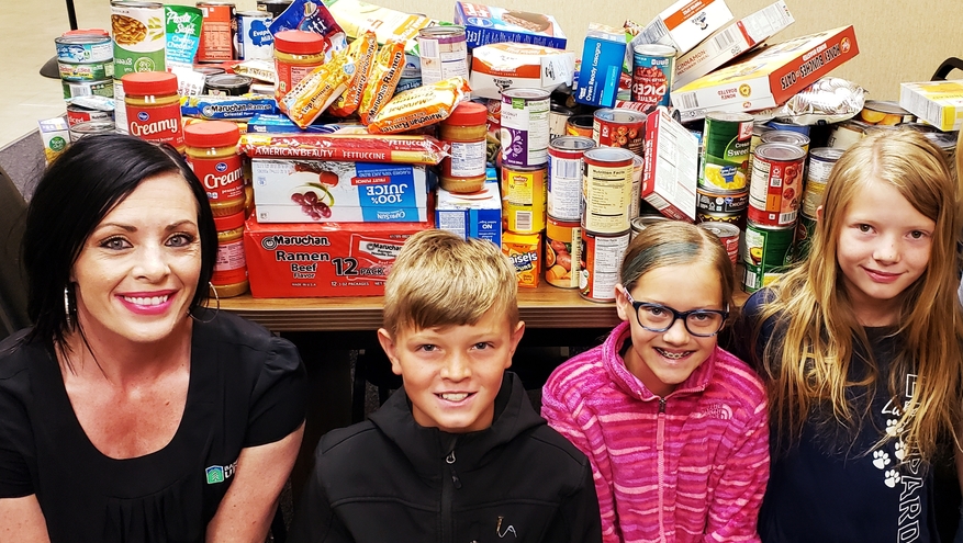 Bank of Utah branch manager with elementary school kids with donations from food drive.