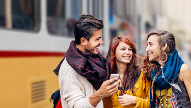 Happy young adults, smiling while holding phone.
