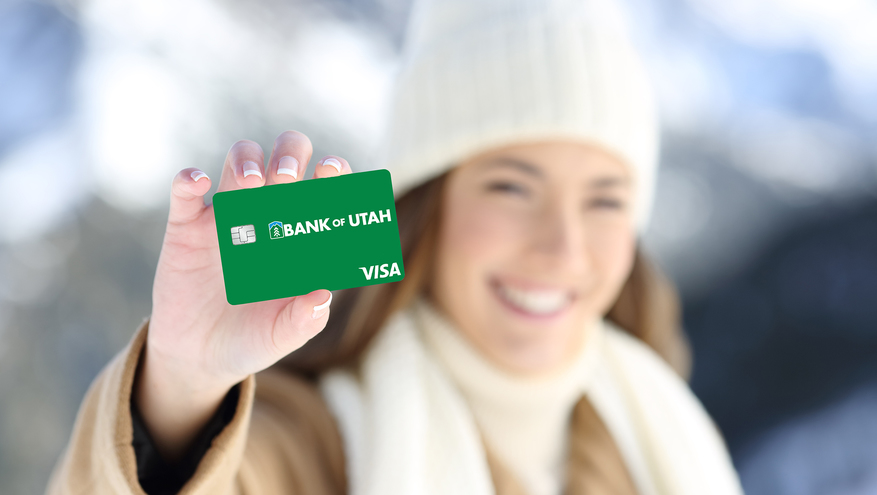 Women holds out a card that could either be a Bank of Utah debit or credit card