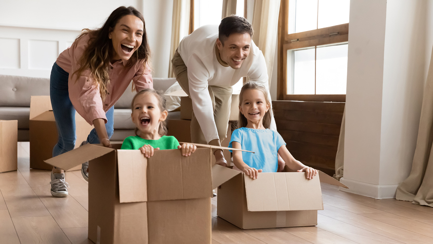 Family moving into new home with children playing in boxes