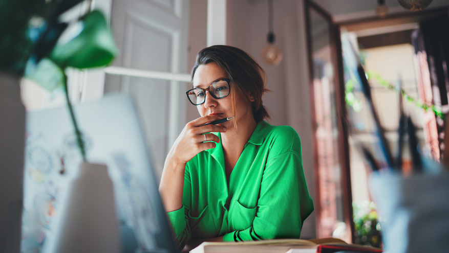 Young business woman looks at computer from her home office