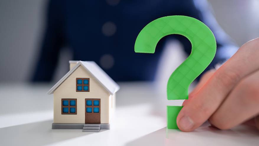 Professional man holding a question mark near a miniature home