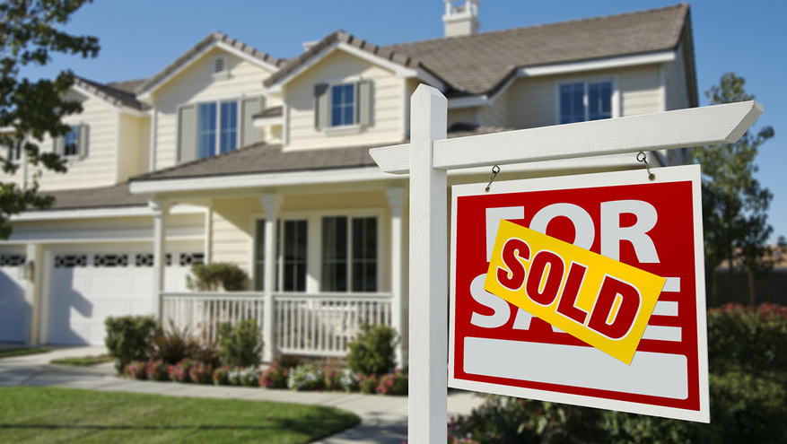 A sold sign is posted in the yard of a townhome